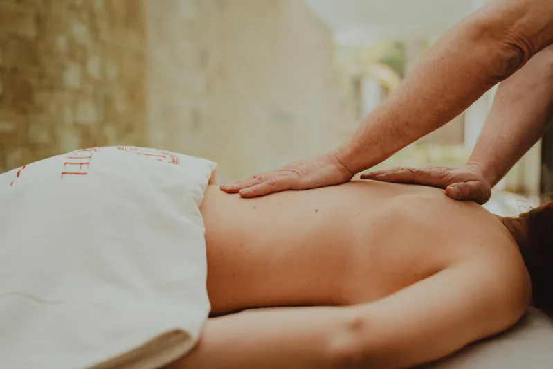 Therapist providing a back massage to an adult.