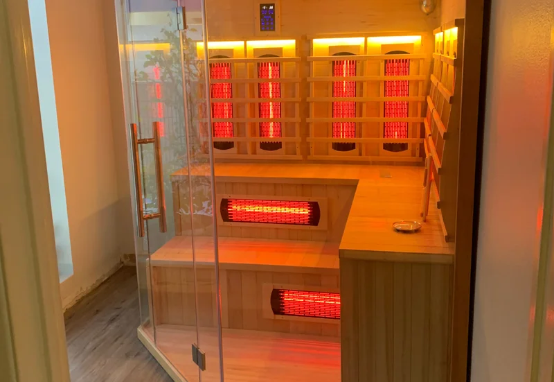 Vitality’s wooden sauna interior with a glass door, benches and glowing heater panels.