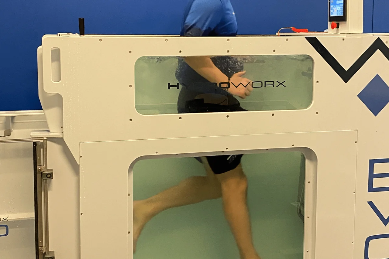 Cropped view of a person’s torso and legs running in a HydroWorx underwater treadmill.