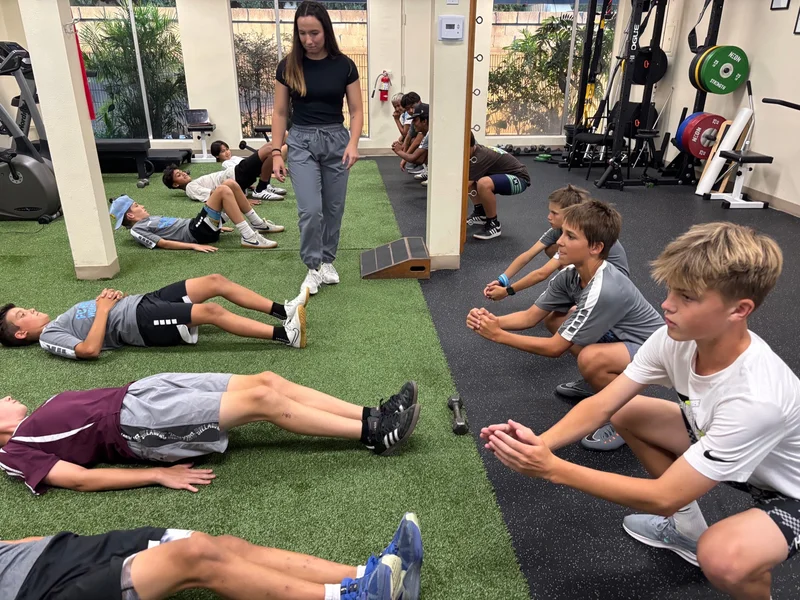 Young athletes doing floor exercises and squats together in the gym.